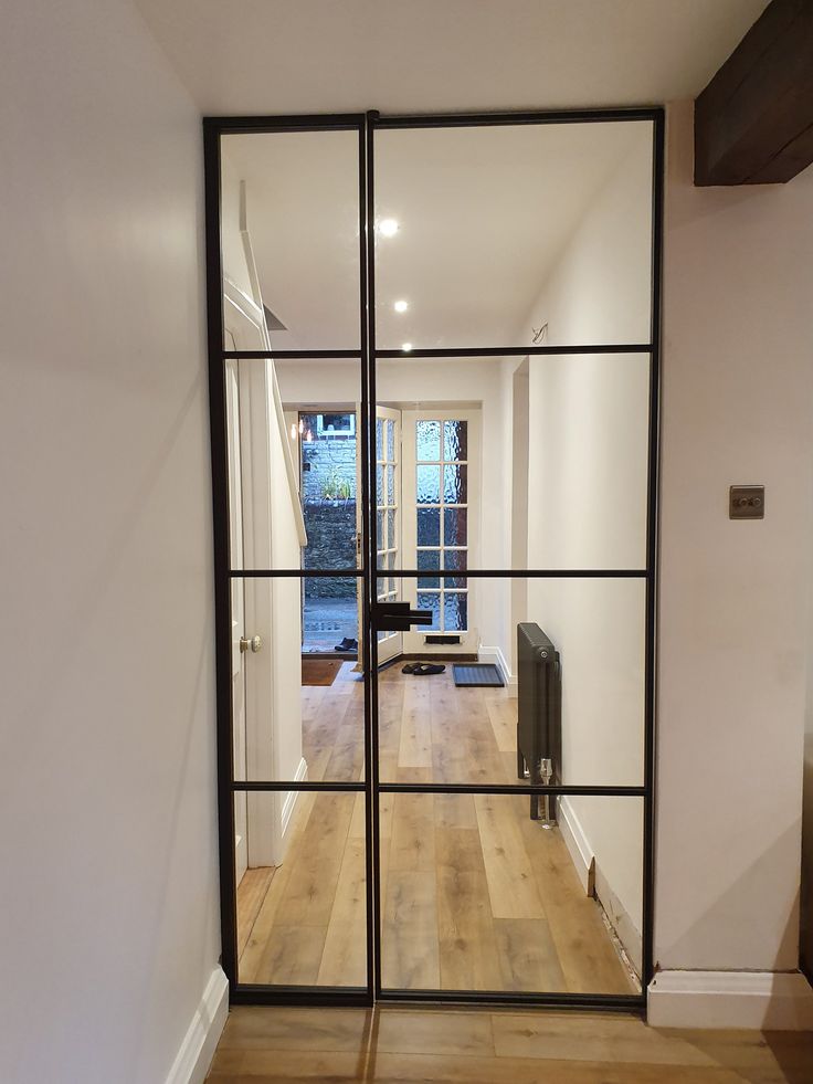 an open glass door leading to a living room with hardwood flooring and white walls