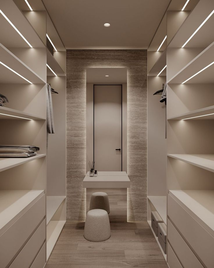 an empty walk - in closet with white shelves and lights on the ceiling is lit by recessed lighting