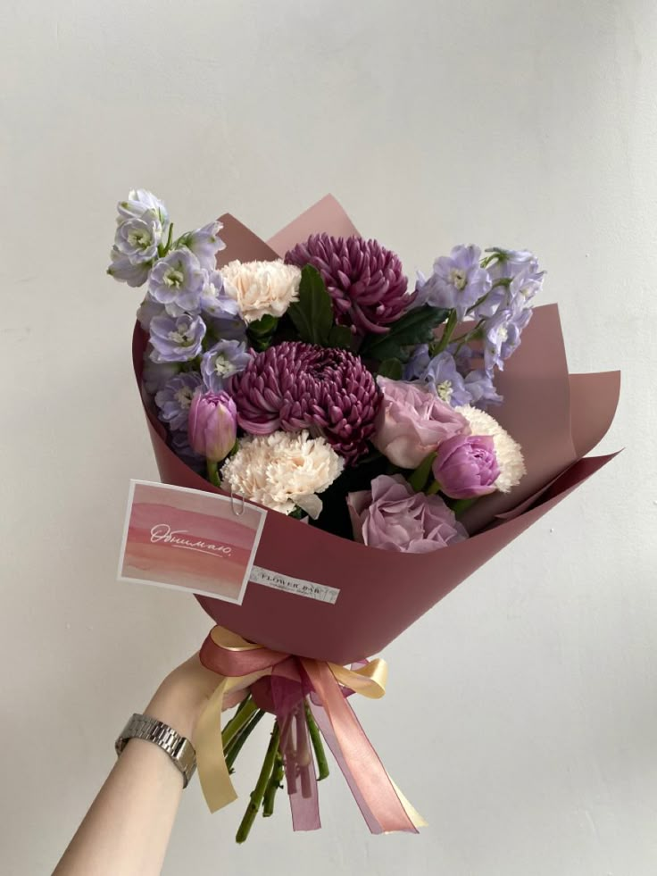 a hand holding a bouquet of purple and white flowers