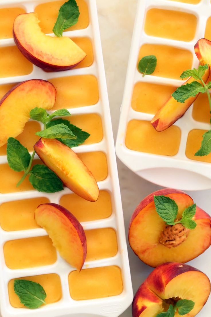 two ice trays filled with sliced peaches and mint