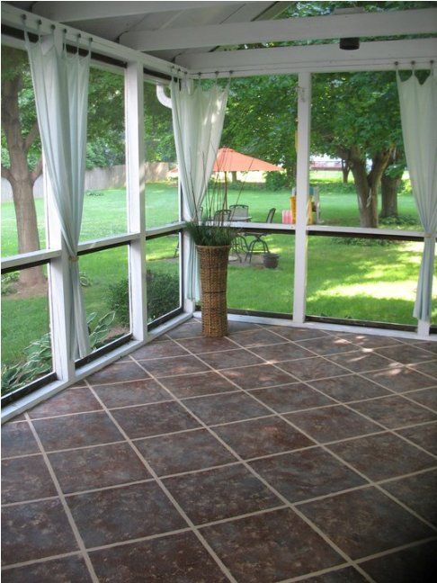 a room with large windows and tile flooring on the outside, looking out onto a grassy area