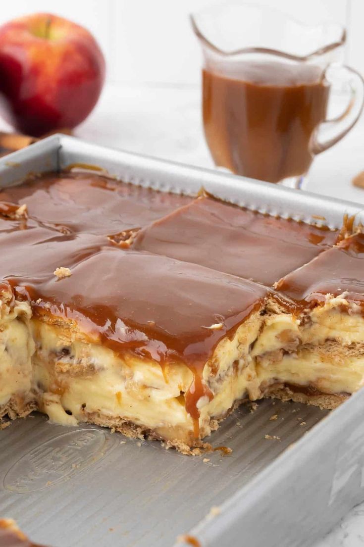 a chocolate caramel dessert on a baking sheet with an apple in the background