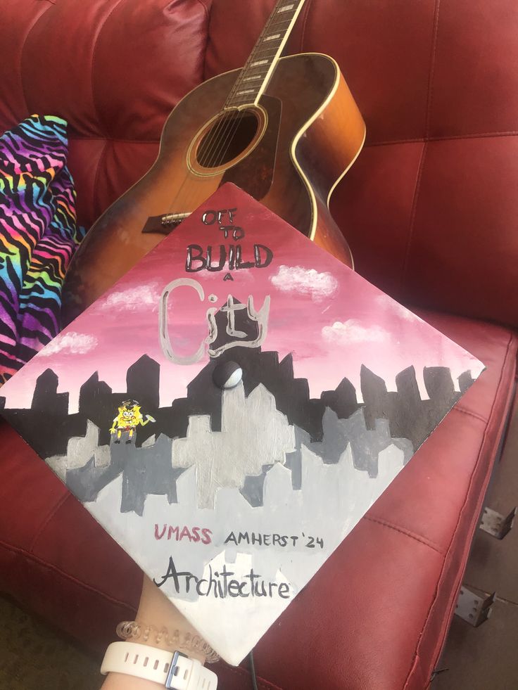 an acoustic guitar is held up in front of a red chair with the words city on it