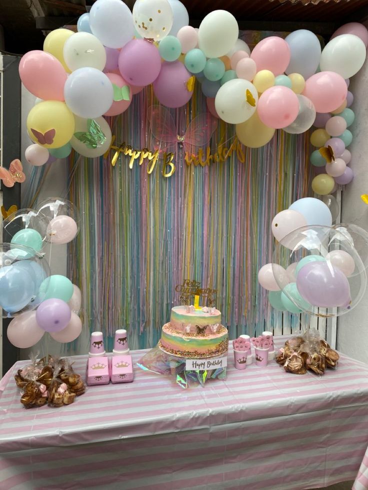 a table topped with a cake and balloons