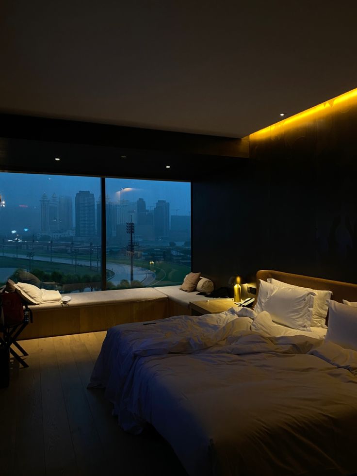 a large bed sitting next to a window in a room with tall buildings behind it