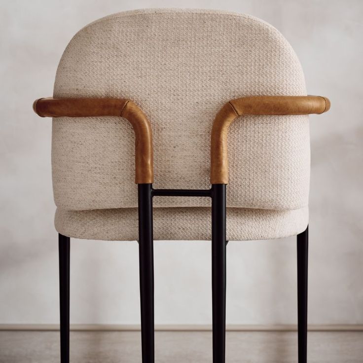 two wooden handles on the back of a chair with a beige upholstered seat