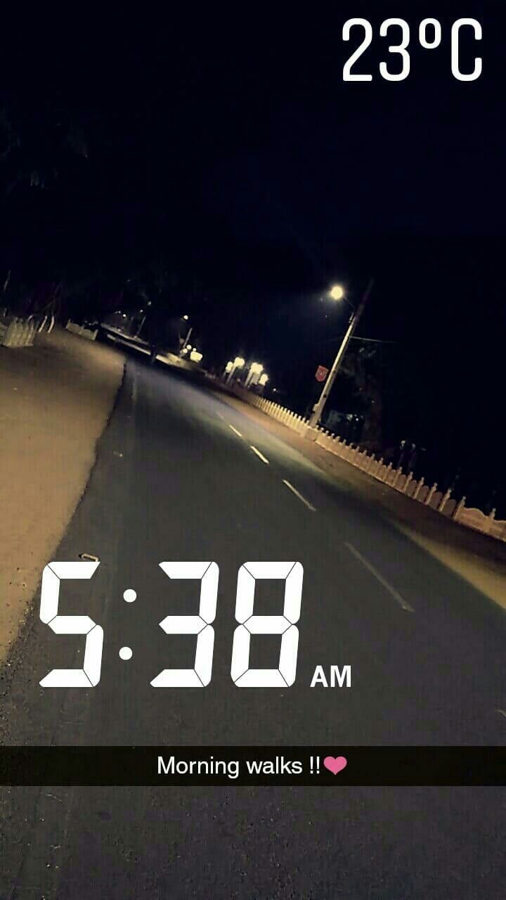 an alarm clock is displayed on the side of a road at night with no traffic