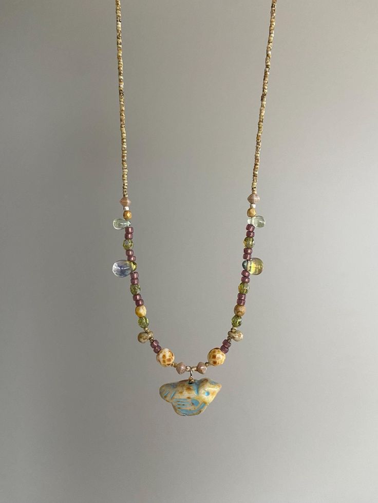 a necklace with beads and charms hanging from it's sides on a chain that is attached to a wall