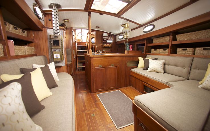 the interior of a boat with wood flooring and couches on each side of the room