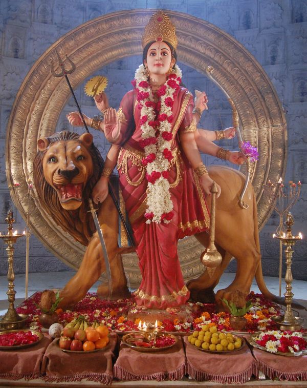 a statue of the hindu god sitting on top of a lion and surrounded by other items