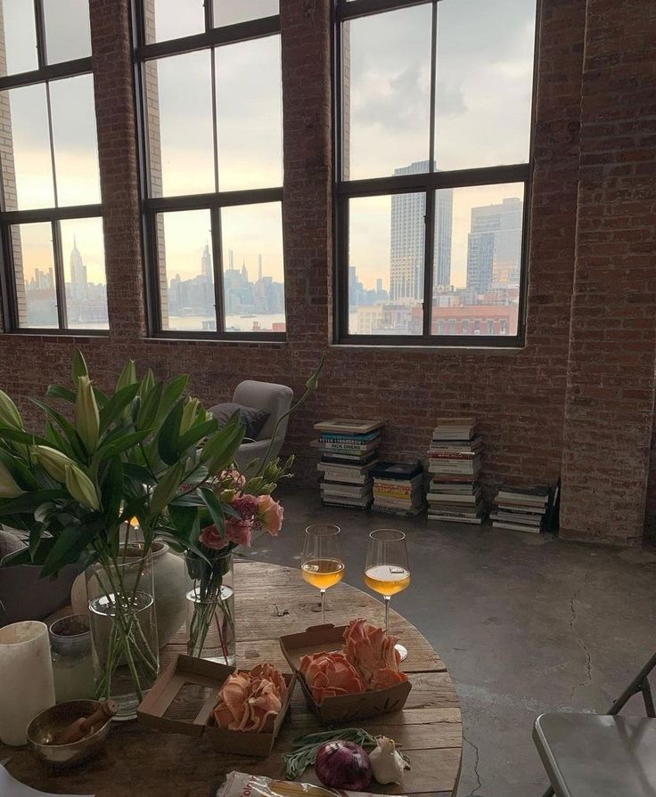 a table with food and drinks on it in front of large windows overlooking the city