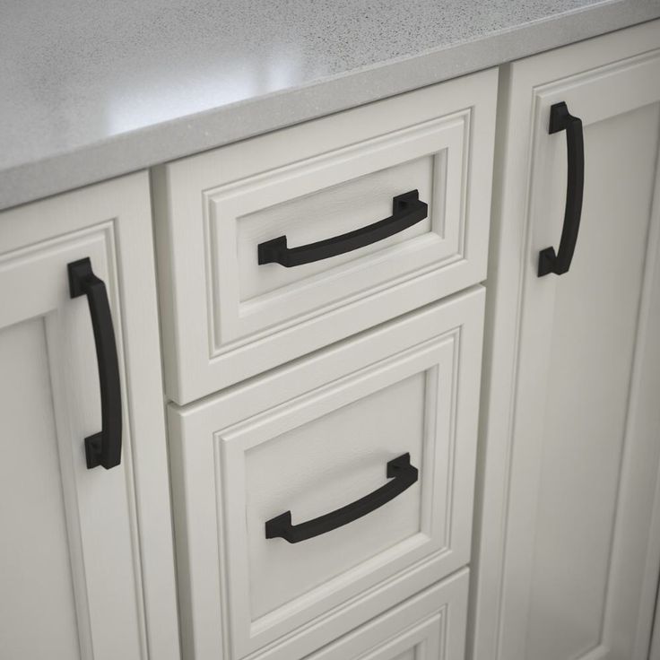 a white kitchen with black handles on the cabinet doors and drawers that are painted white