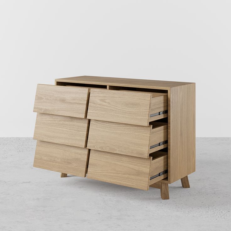 a wooden dresser sitting on top of a cement floor next to a white wall with an open drawer