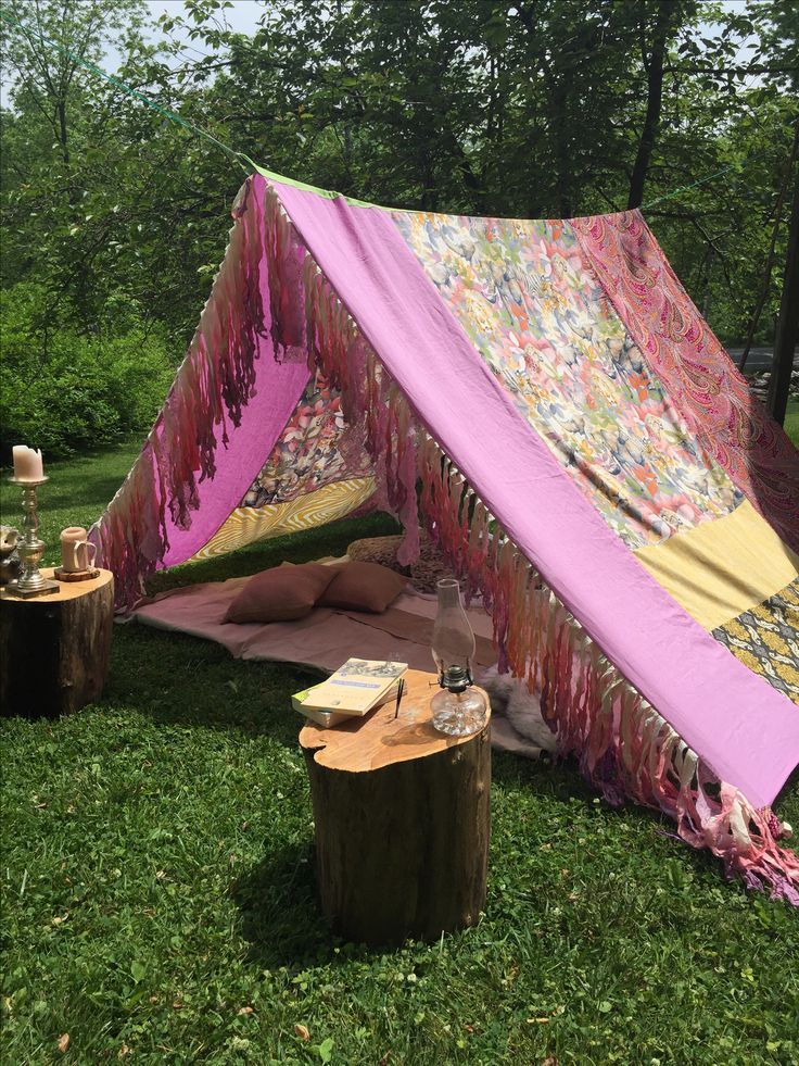 a pink and yellow tent sitting on top of a lush green field next to trees