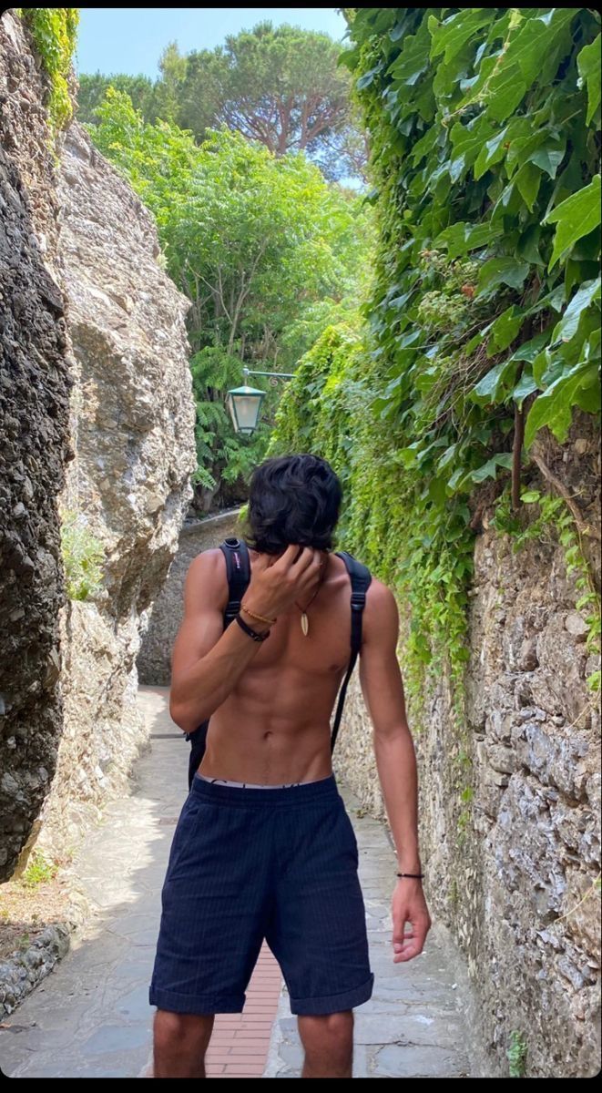 a shirtless man walking down a narrow path