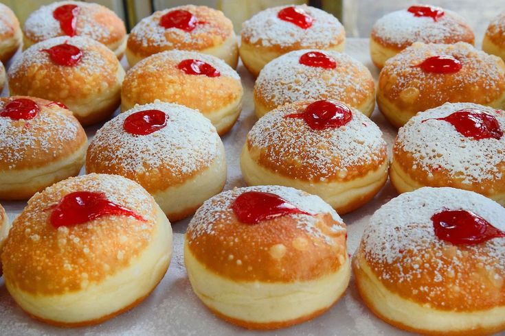 many pastries are covered with powdered sugar and cherries