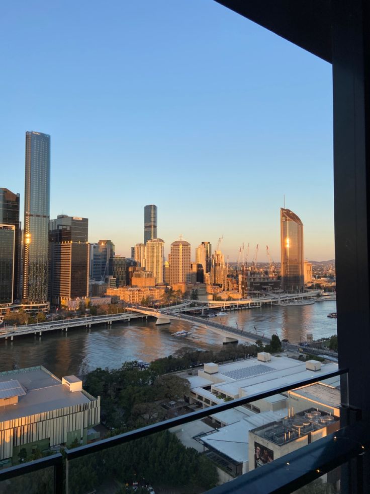 the city skyline is seen from across the river at sunset or dawn, as seen from an apartment balcony