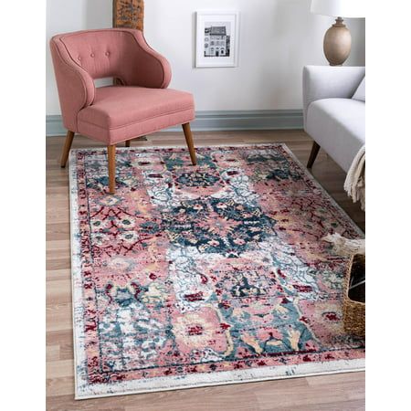 a pink chair sitting on top of a wooden floor next to a white wall and rug