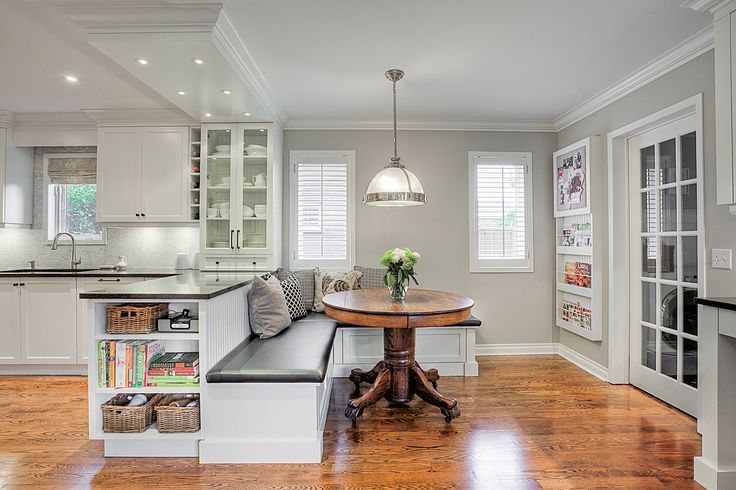 a kitchen with a table, bench and white cupboards in the corner next to it