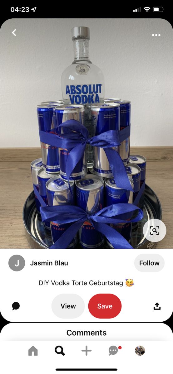 a bottle of vodka sitting on top of a metal tray with blue ribbon around it