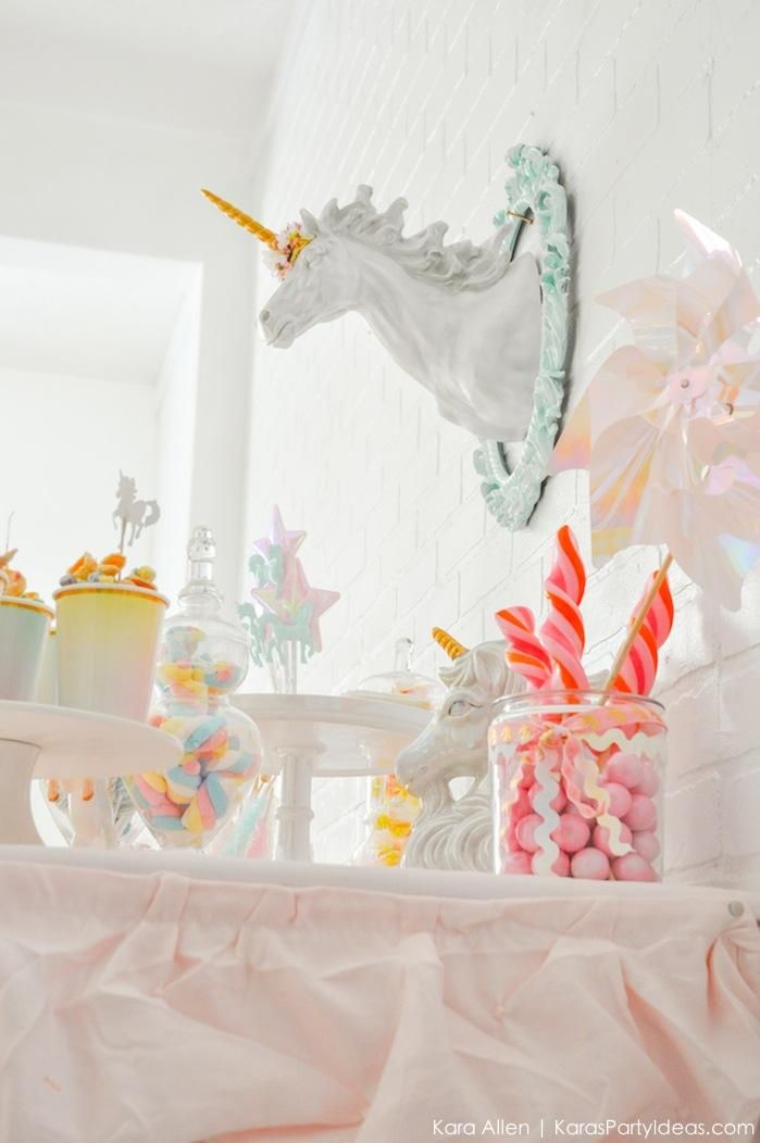 there is a unicorn decoration on the wall above candy and candies in glass vases