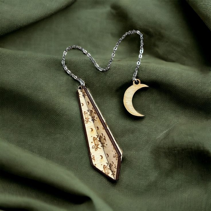 a necklace with a crescent and moon hanging from it's side on a green cloth