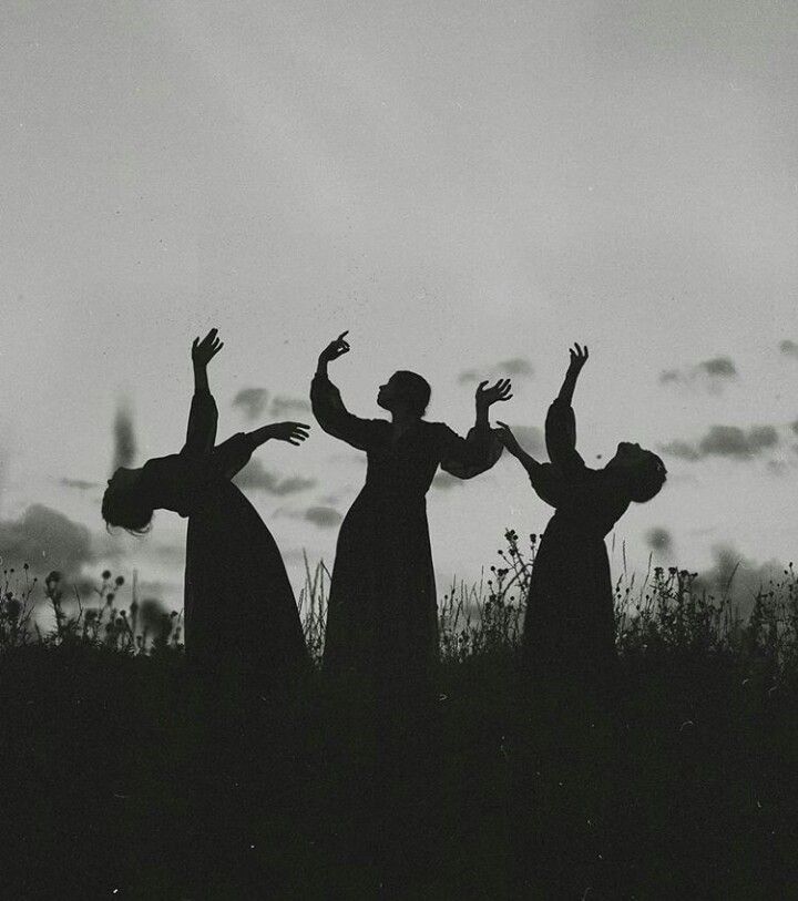 three people standing on top of a grass covered field with their arms in the air