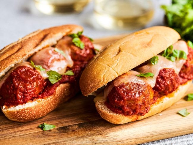 two meatball sub sandwiches on a cutting board