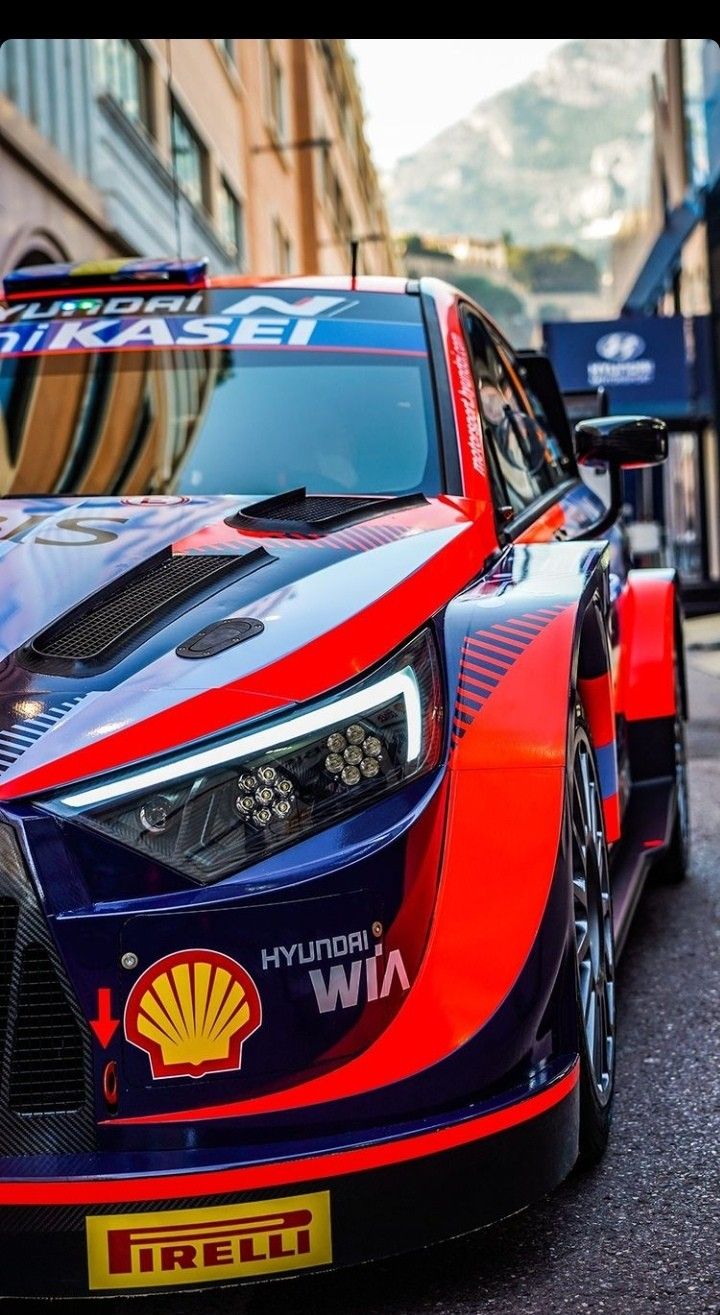 a red and blue race car parked on the side of a street in front of a building