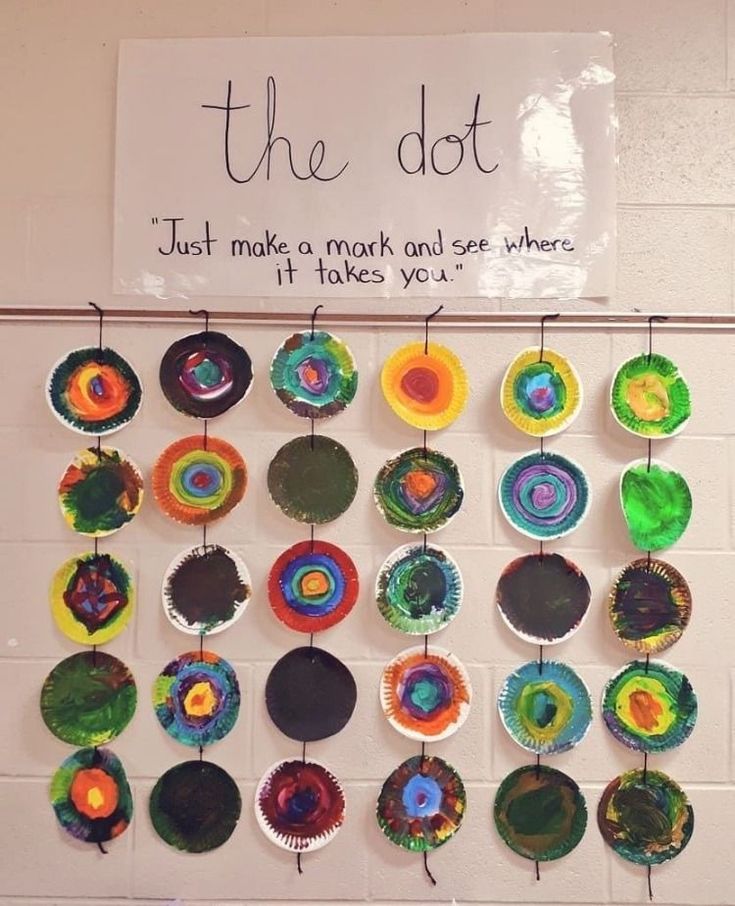 a bulletin board with paper plates hanging from it's sides and a sign that says, the dot just make a mark and see where it takes you