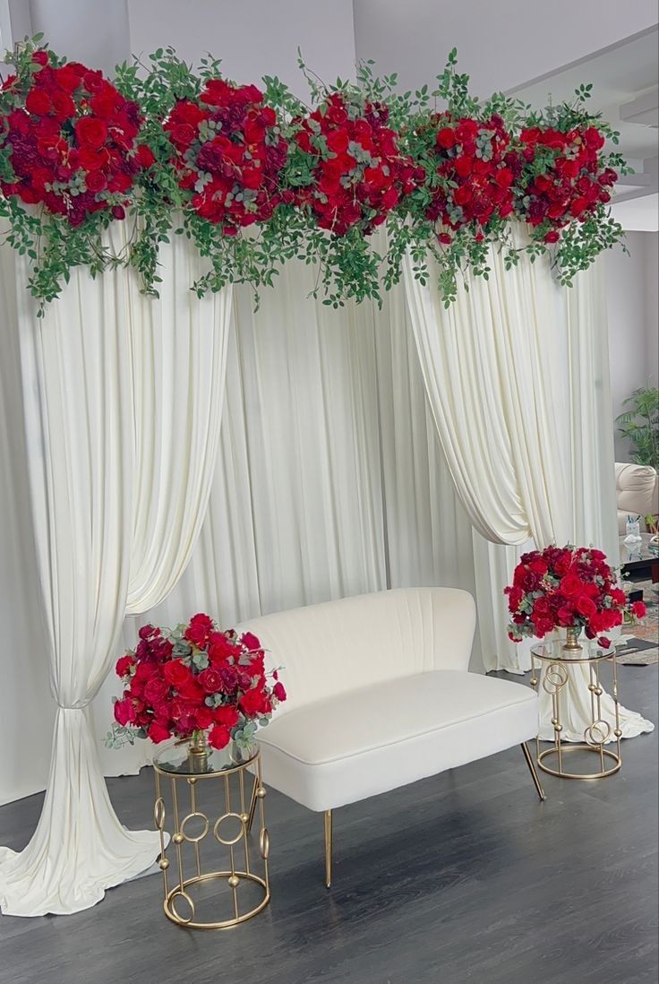 a couch and table with flowers on it in front of a white curtained room