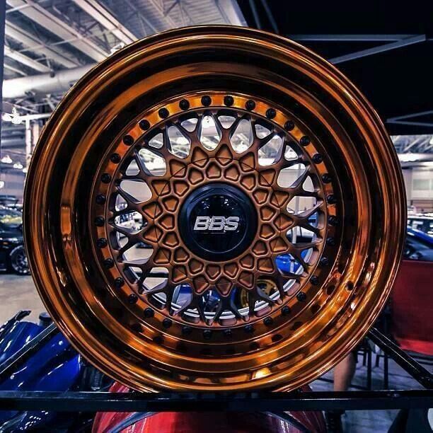 an image of a wheel on display in a car showroom with other cars behind it