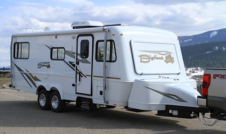 an rv parked in a parking lot with mountains in the background