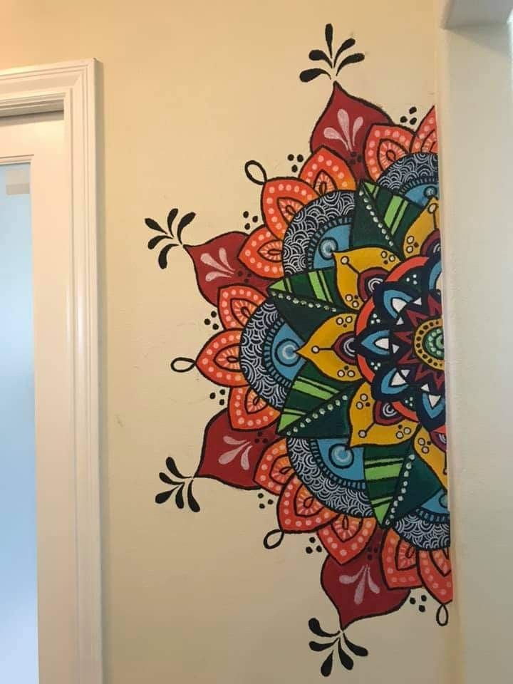 a colorful flower painted on the wall next to a door with a window in it