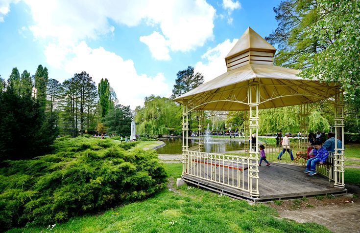 people are walking around in the park under a gazebo with a lake behind it