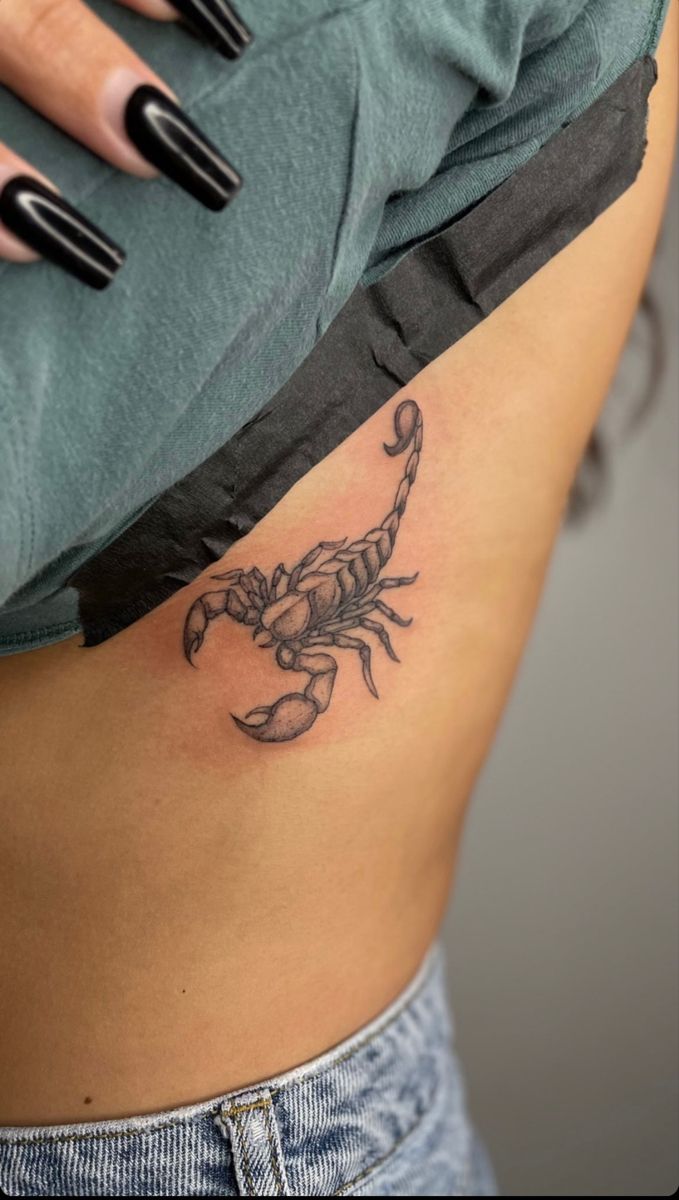 a woman's stomach with a scorpion tattoo on it