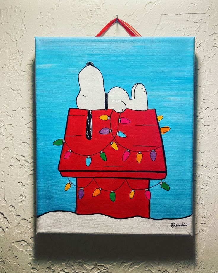 a painting of snoopy on top of a red box with christmas lights hanging from it