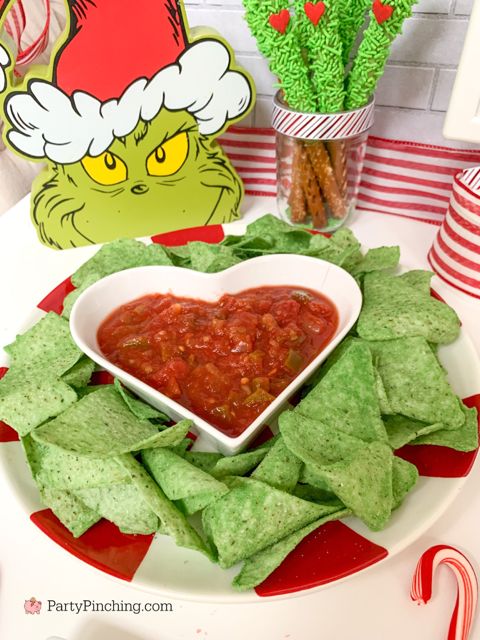 a heart shaped bowl filled with salsa surrounded by tortilla chips