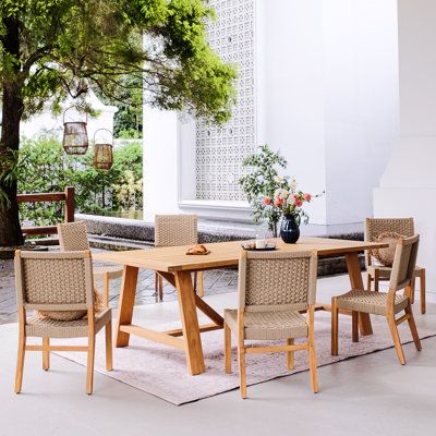 an outdoor dining table and chairs set up in front of a tree with potted plants