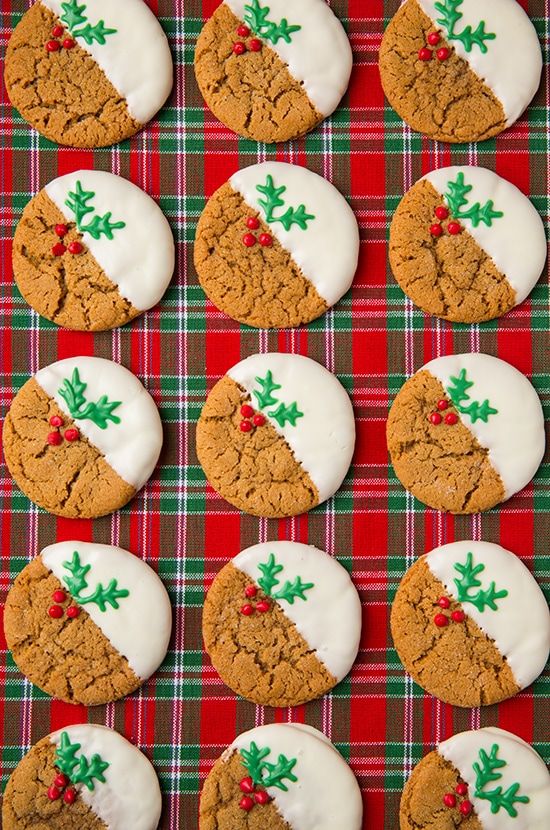 cookies decorated with icing and holly decorations on a red plaid tablecloth, ready to be eaten