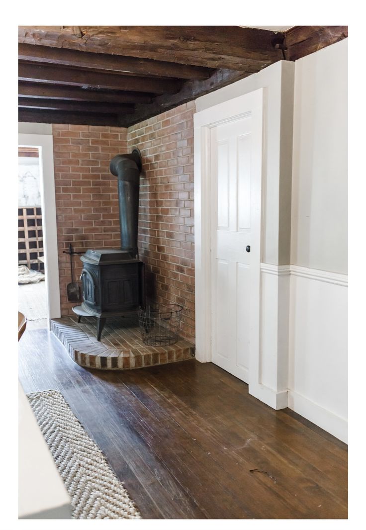 an old fashioned stove in the corner of a room with brick walls and wood floors