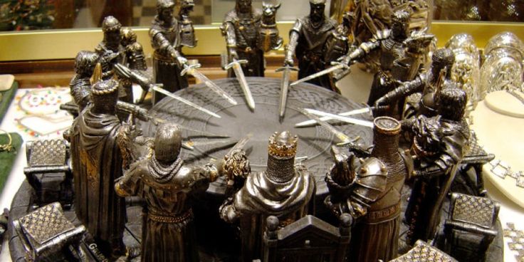 there is a cake decorated with knights and swords on top of the table in front of other cakes