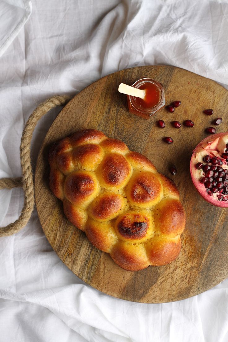 a hot cross bun with pomegranate and honey on a wooden cutting board