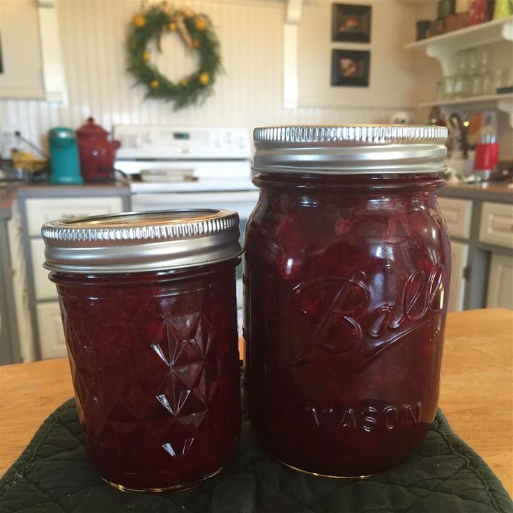 two jars of jam sitting on top of a wooden table