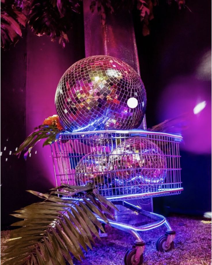 a shopping cart with a disco ball in the back and palm leaves on the side