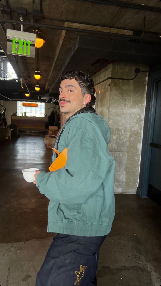 a man standing in a parking garage holding a white bowl and looking at the camera