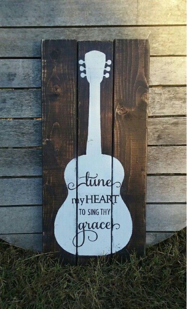 a wooden sign that says tune the heart to sing the peace with an acoustic guitar on it