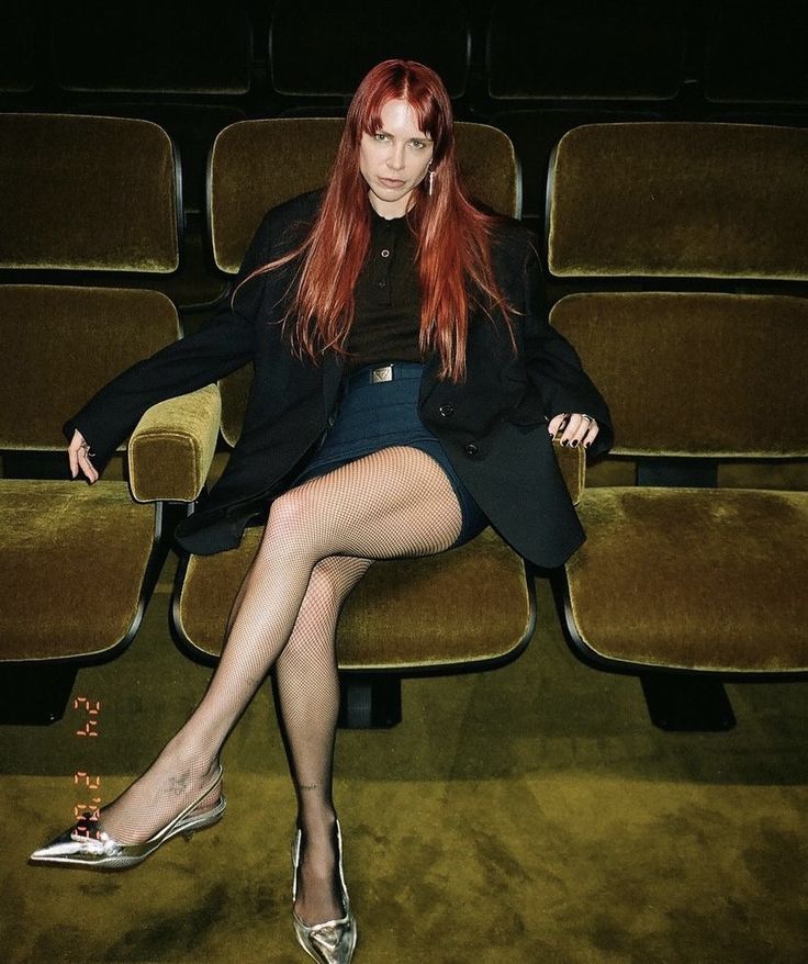 a woman with red hair sitting on a chair in front of a row of chairs