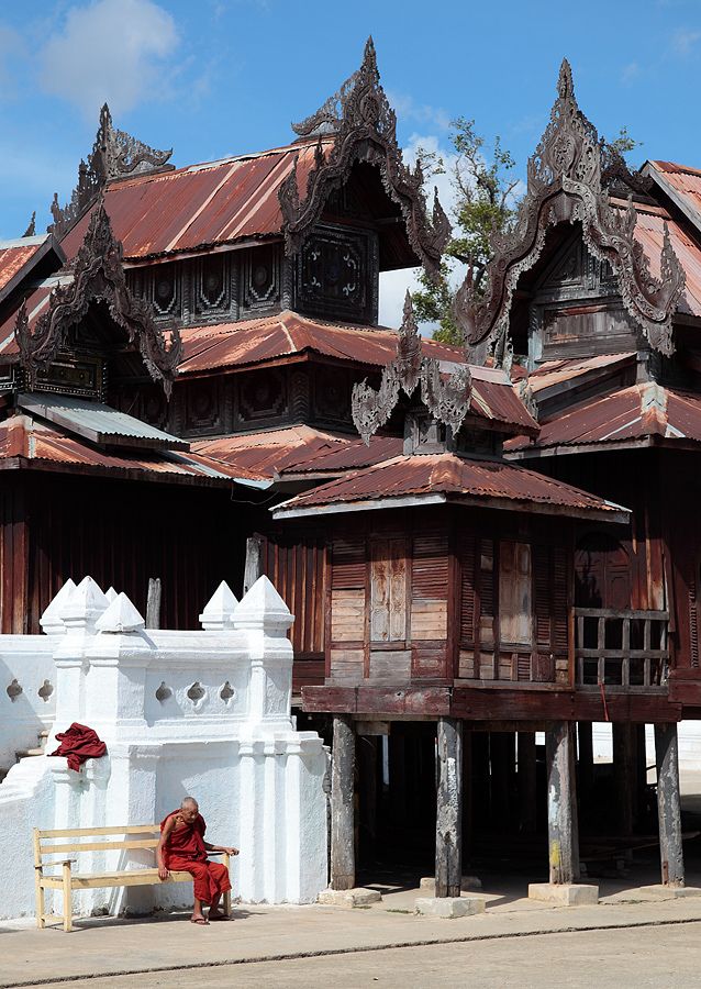 a person sitting on a bench in front of a building with ornately decorated roof tops