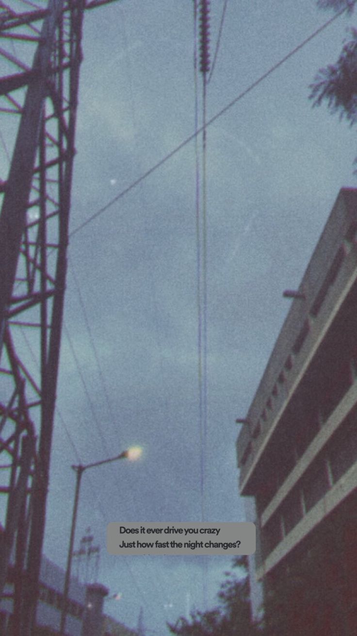 an old photo of some power lines in the sky with buildings and trees behind it